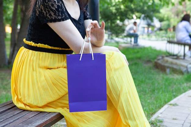 Femme tenant un sac-cadeau alors qu'il était assis sur un banc