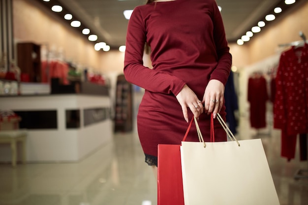 Femme tenant des sacs à provisions en se tenant debout sur la devanture du magasin dans le concept de consommation de fond du centre commercial