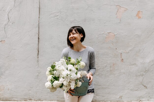 Femme tenant un seau avec des fleurs d'hortensia