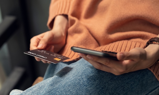 Femme tenant un smartphone et une carte de crédit