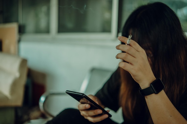 Femme tenant un smartphone et insistant sur le concept de mode de vie malsain de cigarette à la main de travail