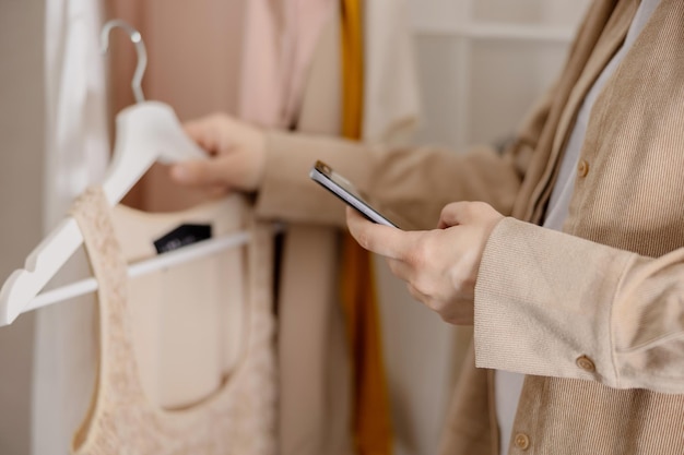 Femme tenant un smartphone et prenant une photo de ses vieux vêtements pour les vendre en ligne