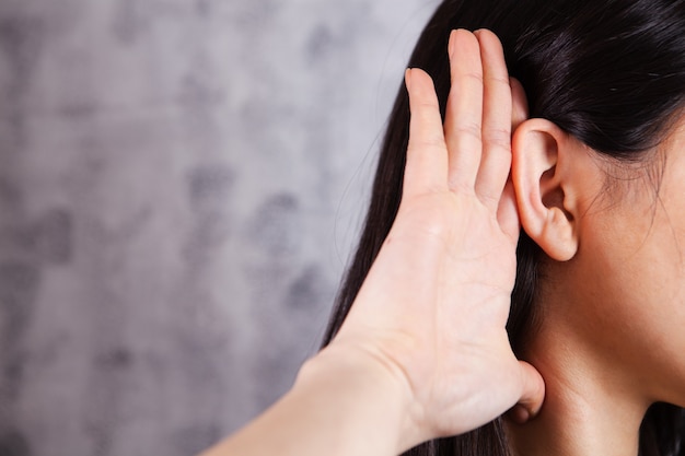 Femme tenant son oreille et écoutant sur gris