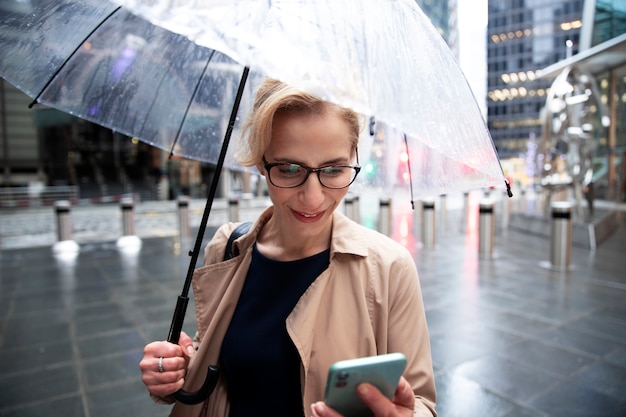 Femme tenant son parapluie et appelant quelqu'un tout en étant dehors quand il pleut