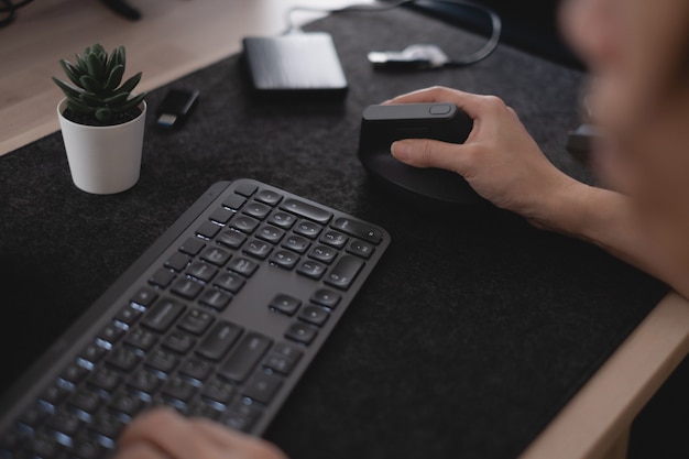 Femme tenant une souris ergonomique sur table