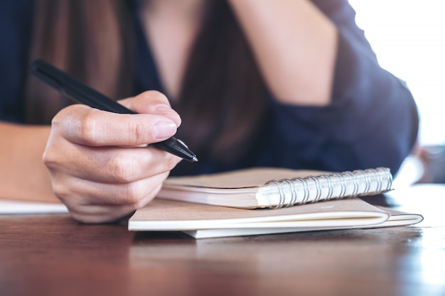 Une femme tenant un stylo pour écrire sur une table en bois