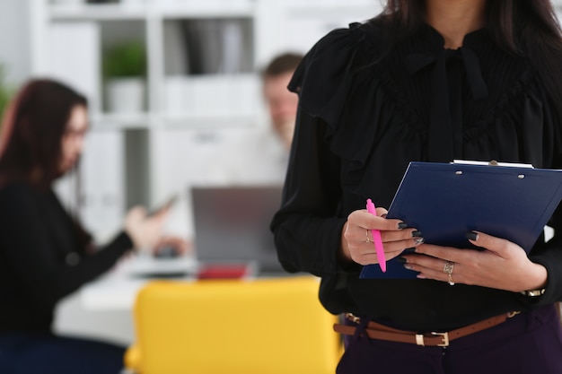 Femme tenant un stylo rose et presse-papiers