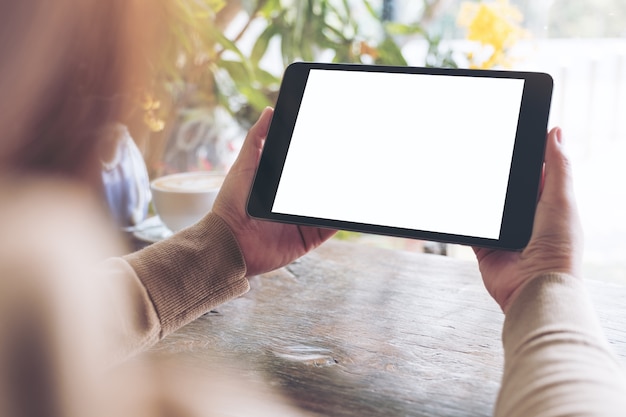 une femme tenant un tablet pc noir avec écran de bureau blanc blanc dans le café