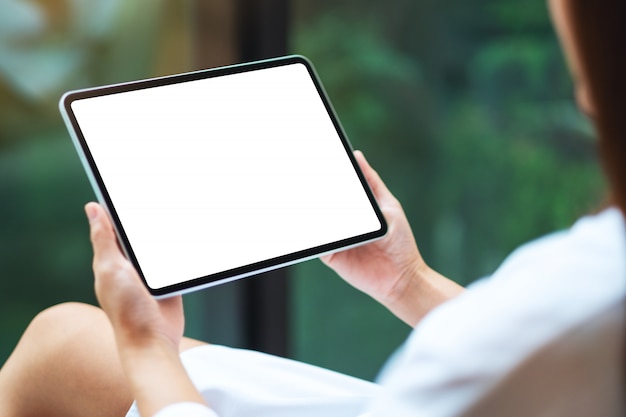 d'une femme tenant un tablet pc noir avec écran de bureau blanc blanc, nature verte