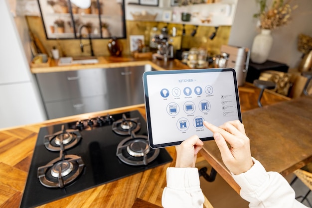 Photo femme tenant une tablette numérique avec une application de maison intelligente en cours d'exécution dans la cuisine