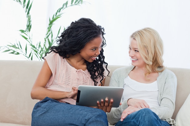 Une femme tenant une tablette tactile sourit à son ami