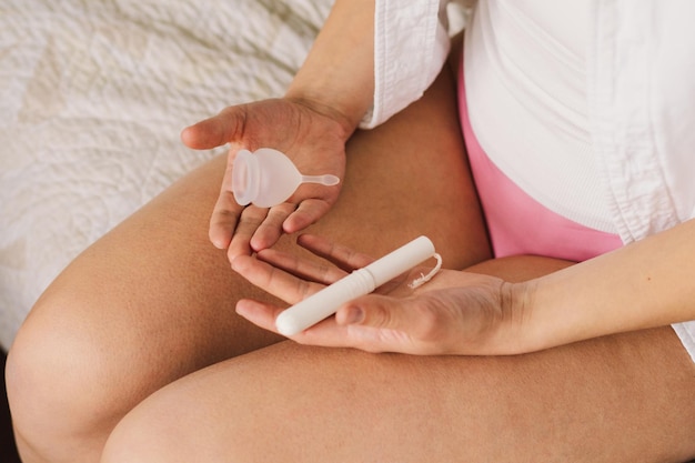 Photo une femme tenant un tampon et une coupe menstruelle