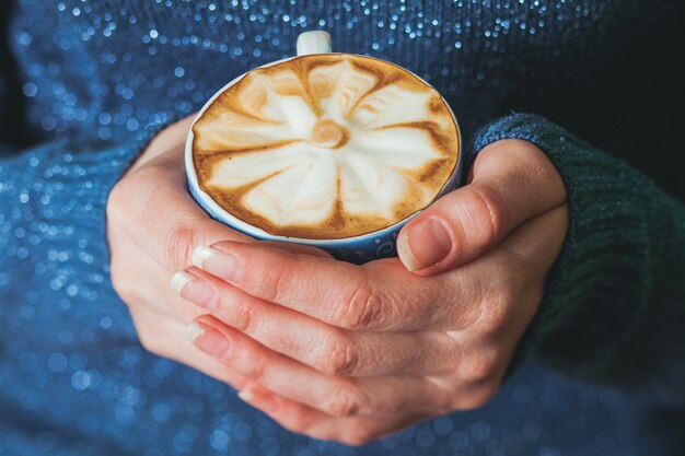 Femme tenant une tasse de café au lait avec beau motif