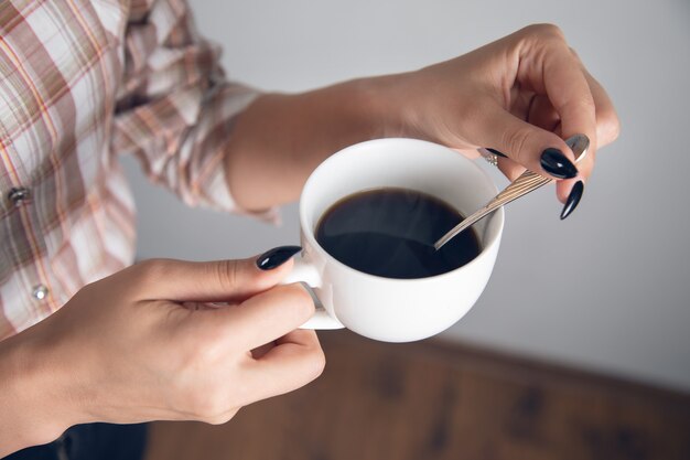 Femme tenant une tasse de café avec une cuillère