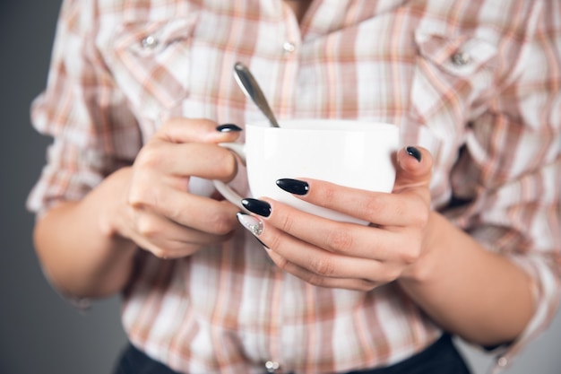 Femme tenant une tasse de café avec une cuillère