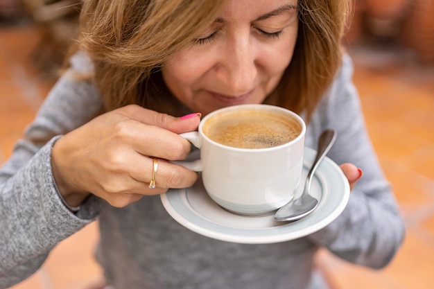 Femme tenant une tasse de café fraîchement préparé tout en sentant l'arôme du café