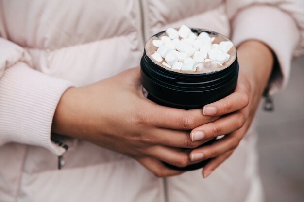 Femme tenant une tasse de café réutilisable en hiver