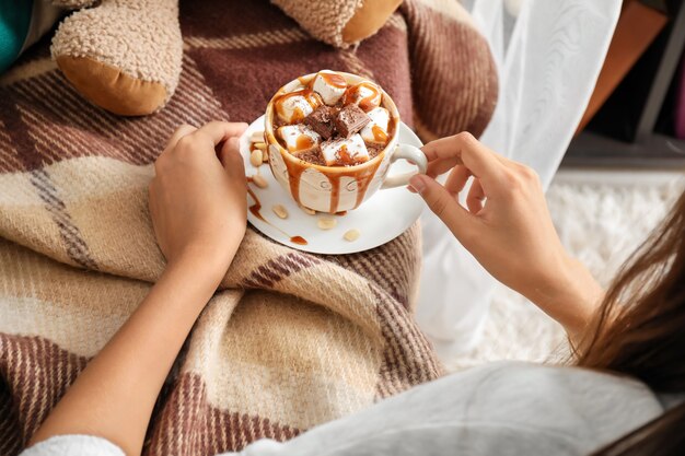 Femme tenant une tasse de chocolat chaud avec des guimauves