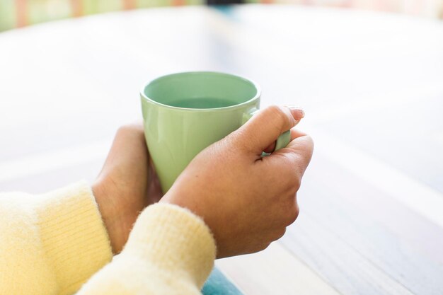 Femme tenant une tasse d'eau sur une table