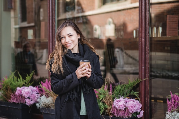 Femme tenant une tasse sur le fond urbain