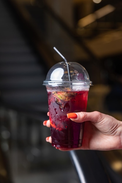 Une femme tenant une tasse de jus de fruits