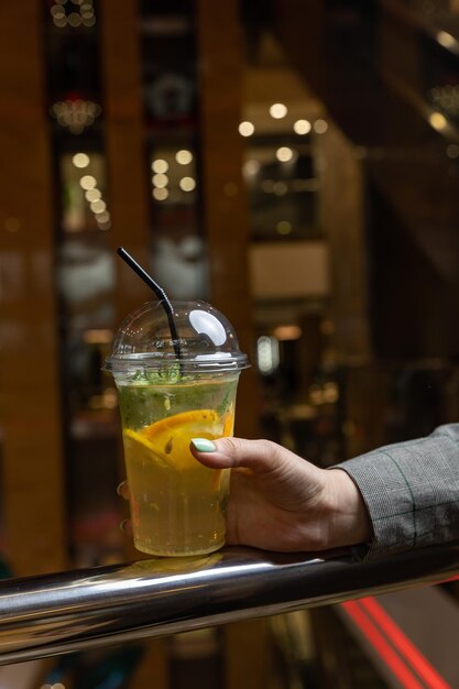 Une femme tenant une tasse de limonade avec une paille