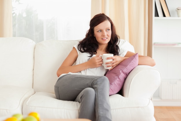 Femme tenant une tasse regardant par la fenêtre