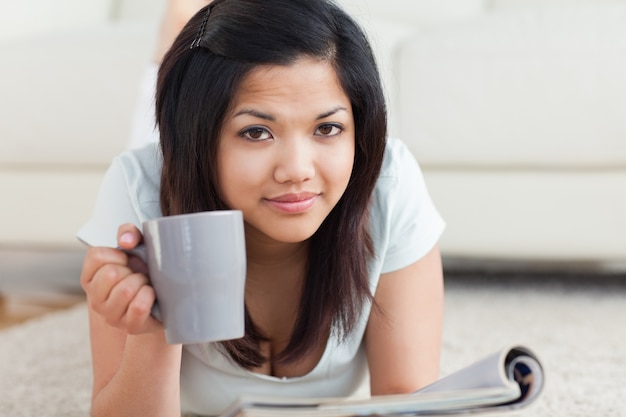 Femme tenant une tasse sur le sol en lisant