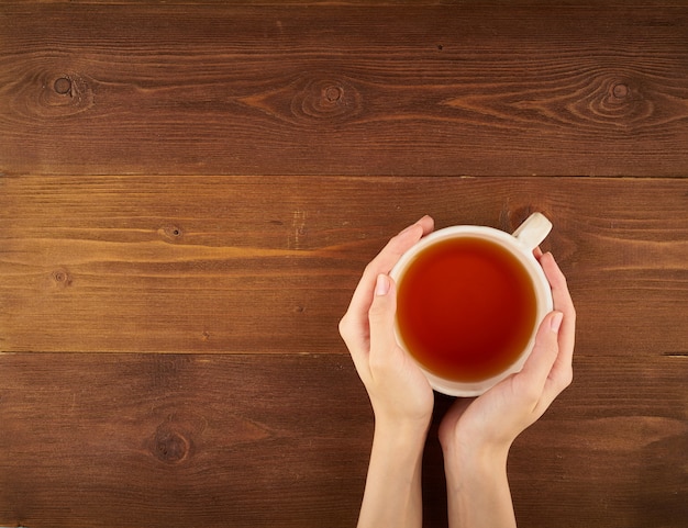 Femme tenant une tasse de thé sur bois foncé