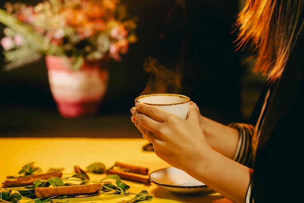 Femme tenant une tasse de thé chaud fraîchement infusé et prêt à boire