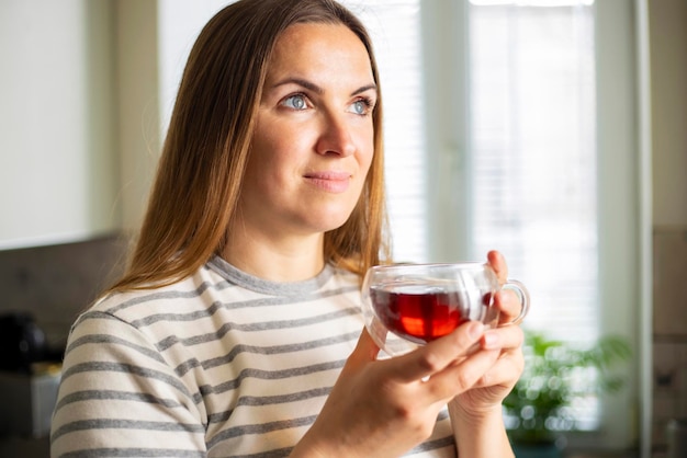 Une femme tenant une tasse de thé chaud le matin