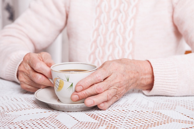 femme tenant une tasse de thé dans ses mains.