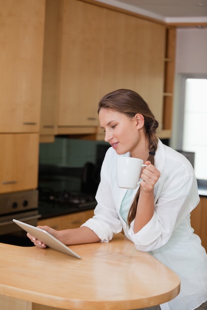 Femme tenant une tasse tout en regardant une tablette PC