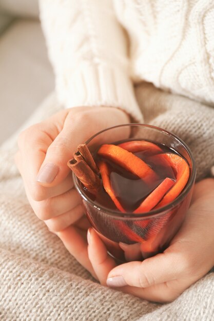 Femme tenant une tasse en verre de délicieux vin chaud de Noël dans les mains, gros plan