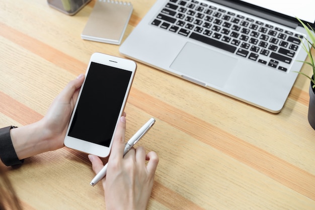 Femme tenant un téléphone à écran blanc et un ordinateur portable et mettre une montre intelligente, effet de film.