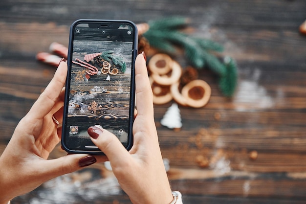 Femme tenant le téléphone fond de Noël avec décoration de vacances