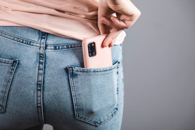 Femme tenant un téléphone intelligent dans la poche de jeans