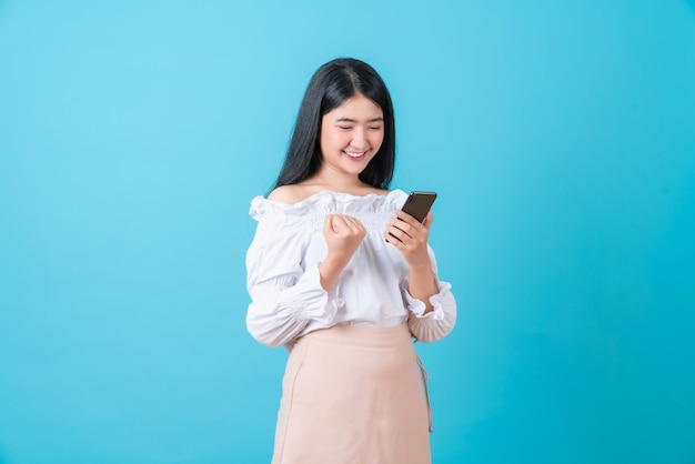 femme tenant un téléphone intelligent avec la main de poing et excité pour le succès.