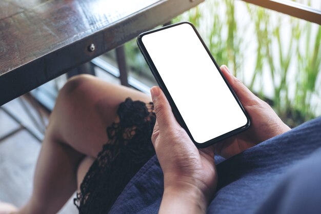 Femme tenant un téléphone mobile noir avec écran de bureau vide alors qu'il était assis dans un café