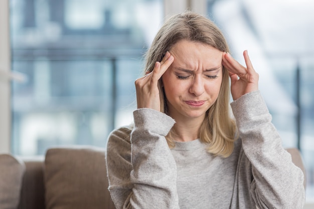 une femme tenant la tête anxieuse à propos d'un mal de tête insupportable