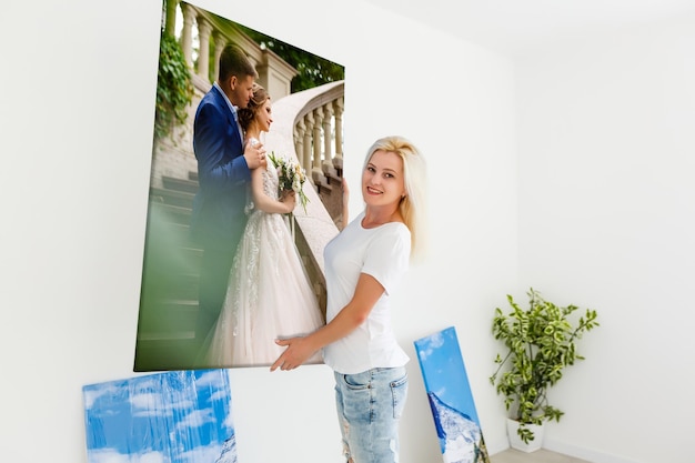 femme tenant une toile photo sur le fond d'un intérieur.