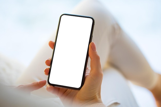 Femme tenant et utilisant un smartphone à la maison Maquette pour téléphone portable avec écran blanc vide