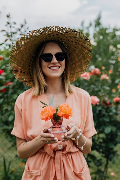 Femme tenant un vase de roses oranges