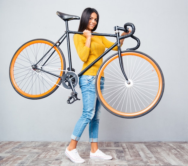 Femme tenant un vélo sur l'épaule