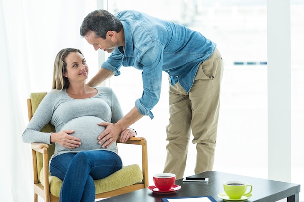 Femme tenant un ventre de femme enceinte dans le salon