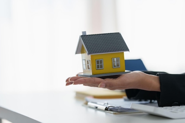 Une femme tenant et vérifiant le modèle de maison Évaluation et inspection de la maison immobilière et concept d'assurance