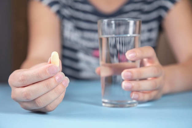 Femme tenant un verre d'eau et de drogue