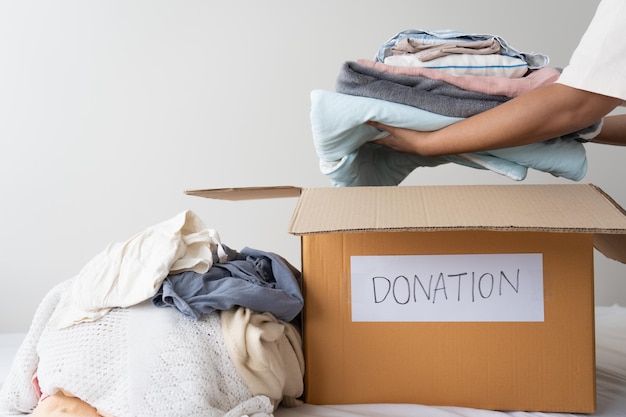 Femme tenant des vêtements mettant dans une boîte de dons Partage d'aide Concept de don