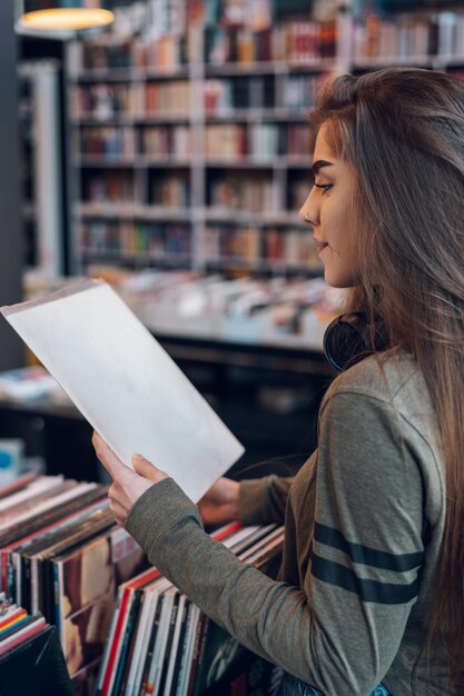 Femme tenant un vinyle tout en choisissant un enregistrement dans un magasin de musique