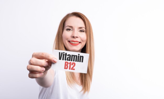 Femme tenir une carte avec mot vitamine B12 sur blanc.